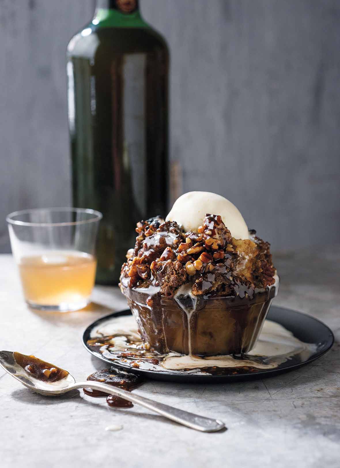 Glass bowl filled with pecan pie bread pudding, caramel sauce, bourbon-vanilla ice cream on a marble table