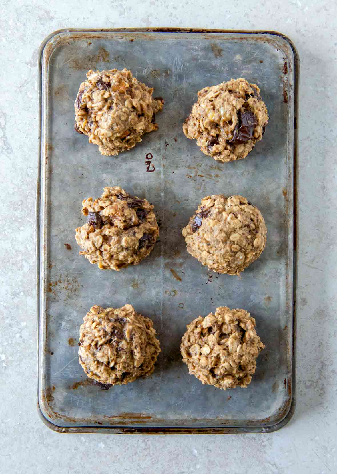 A cookie sheet with six breakfast cookies with oats, banana, figs, and peanut butter