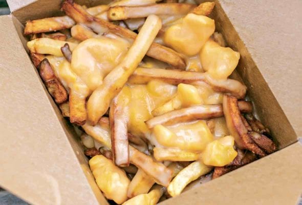 Cardboard container filled with french fries covered in melted cheese curds