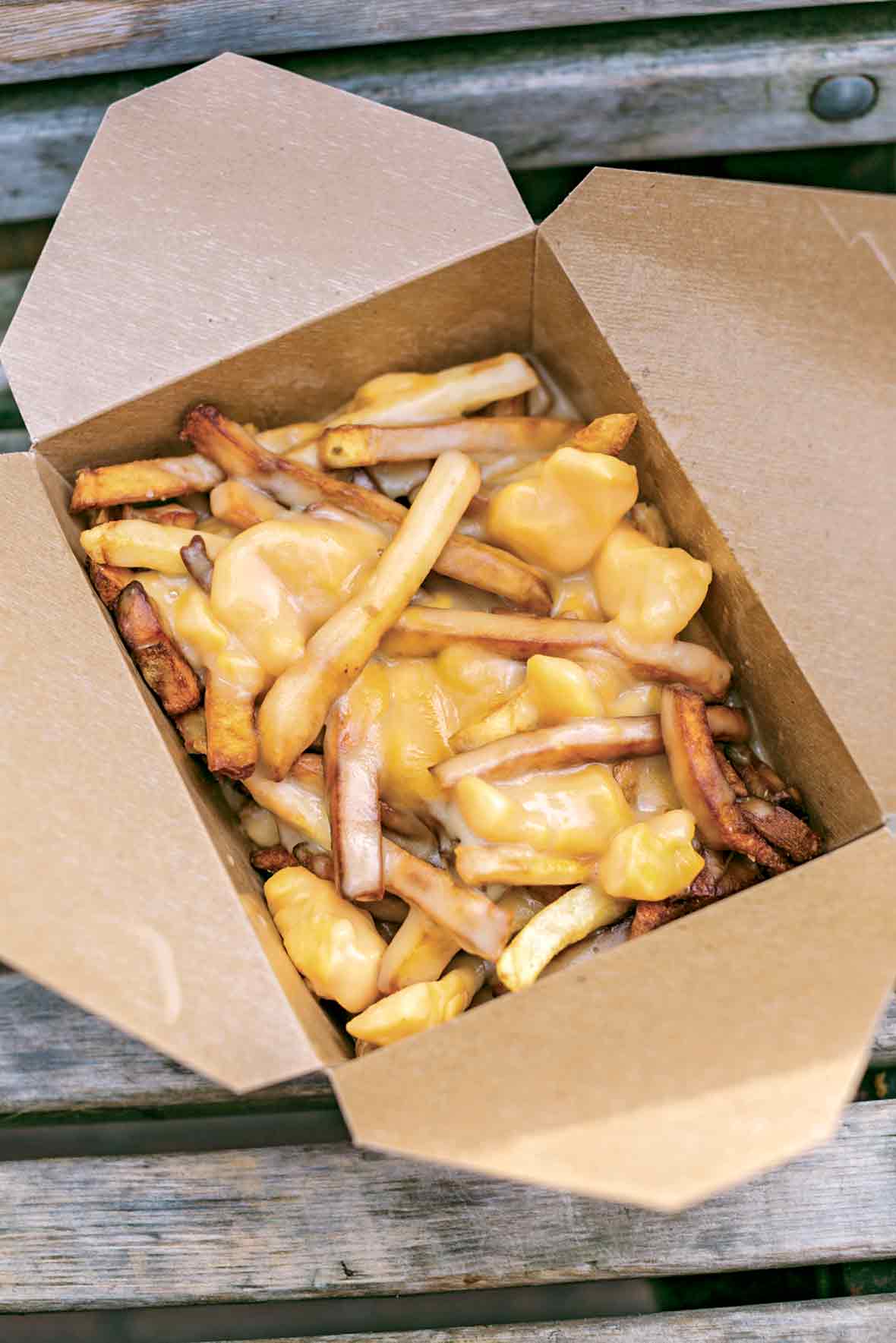 Cardboard container filled with french fries covered in melted cheese curds