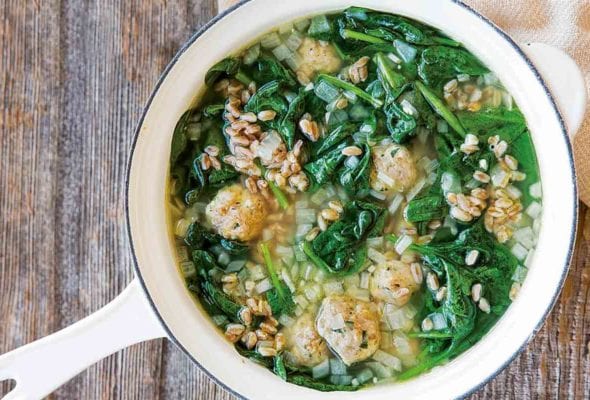 A white enamel pot filled with turkey meatball soup.