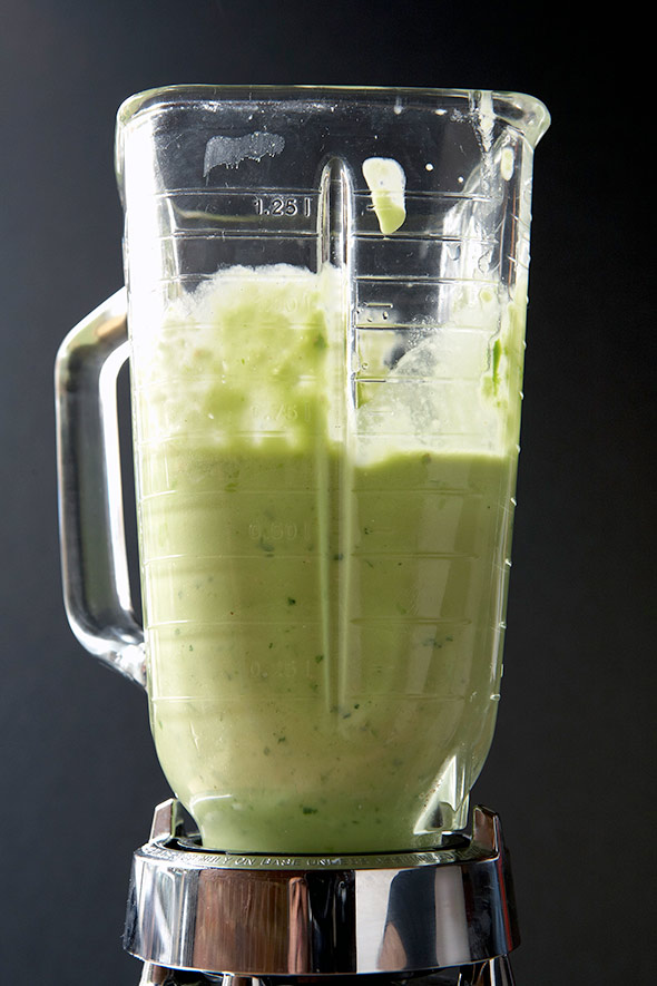 A blender half-filled with tomatillo salsa.