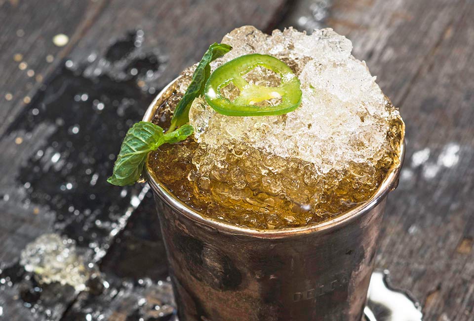 A jalapeno mint julep in a pewter julep cup, topped with a mint sprig and jalapeno slice.