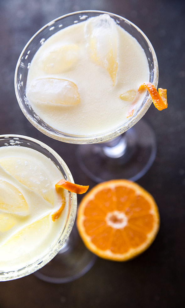 Two martini glasses filled with morir sonando, ice, and orange twists.