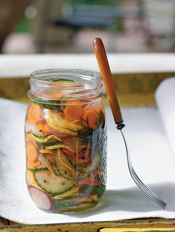 A jar of refrigerator pickles on a white napkin with a fork resting against the jar.