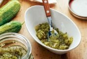 A white bowl of sweet pickle relish with a spoon with a wooden handle in it