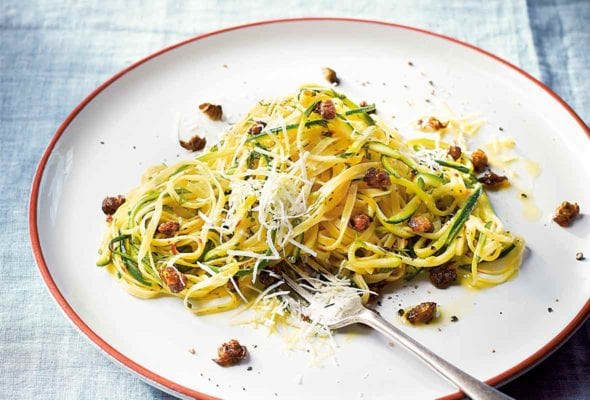 A white plate of zucchini linguine--with pasta, zucchini, garlic, capers, mint, dill, and cheese with a fork