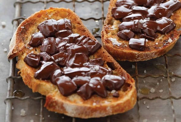 Two slices of chocolate sandwich, made with toasted French bread, chocolate, and a sprinkling of salt on a wire rack.