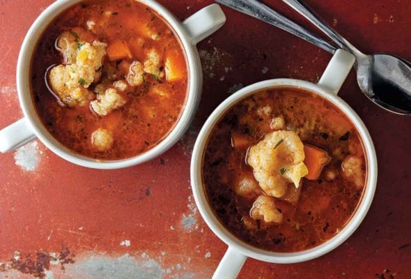 Two bowls of Hungarian cauliflower soup with two spoons resting beside them.