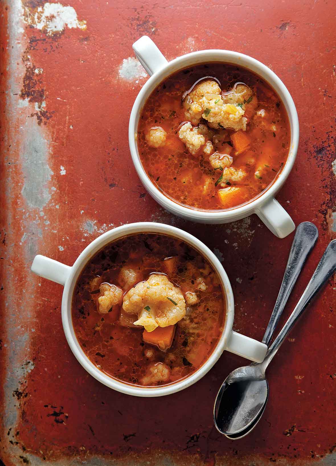 Two bowls of Hungarian cauliflower soup with two spoons resting beside them.