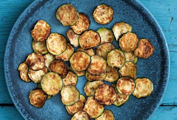 A blue plate filled with slices of zucchini crisps.