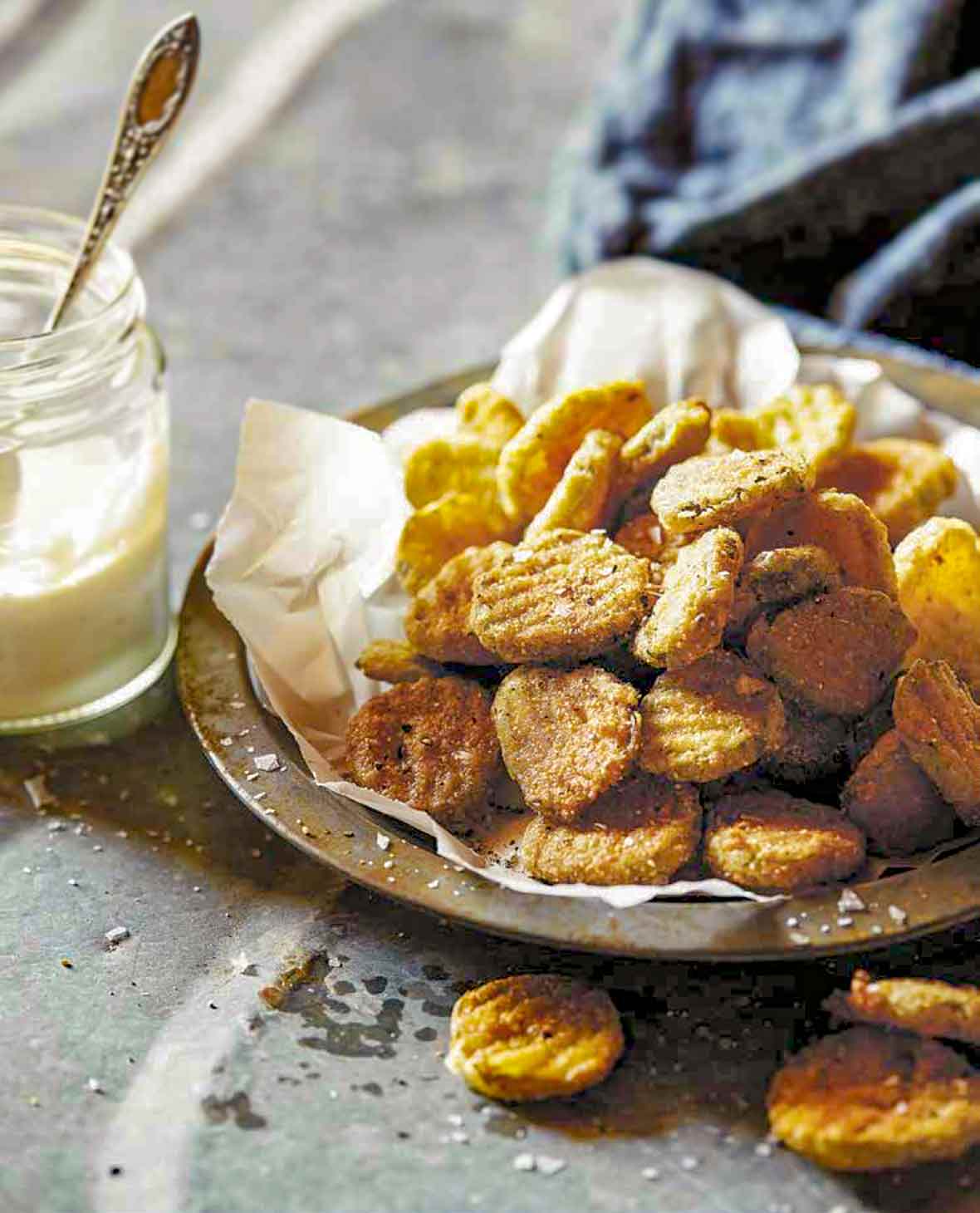 Bowl of batter-covered easy fried pickles with a jar of dipping sauce nearby