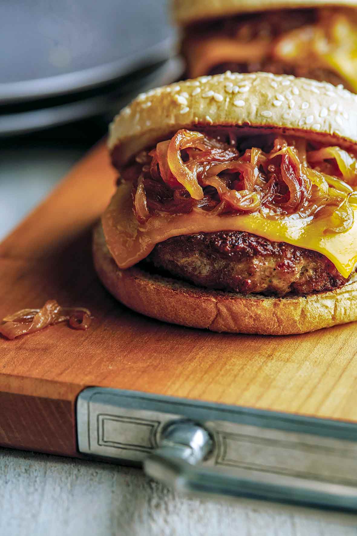 A turkey burger with maple caramelized onions and cheese on a wooden cutting board
