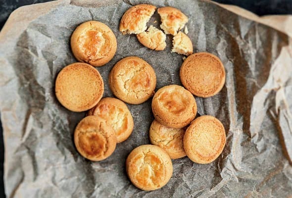Ten whole, plus one broken butter cookies on a piece of crumpled parchment paper