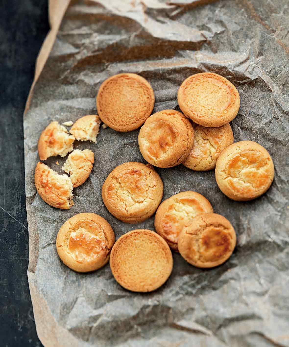 Ten whole, plus one broken butter cookies on a piece of crumpled parchment paper