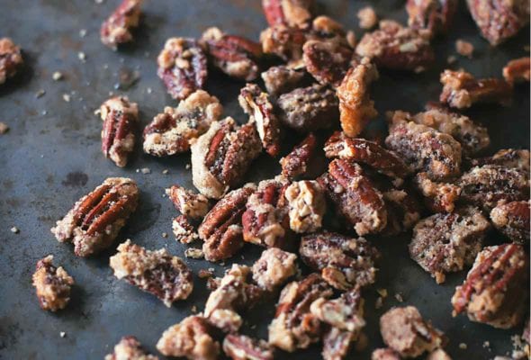 Candied pecans scattered on a dark surface.