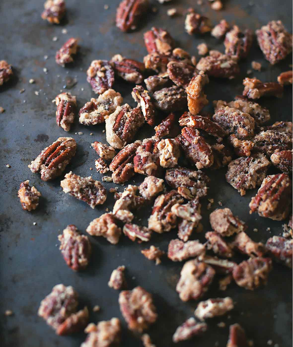 Candied pecans scattered on a dark surface.