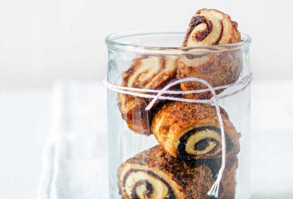 Four cream cheese rugelach in a glass jar with twine wrapped around it.