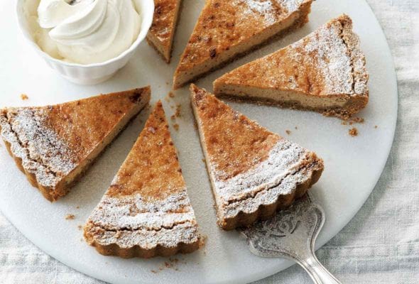 A round white plate with six slices of eggnog pie and a dish of whipped cream