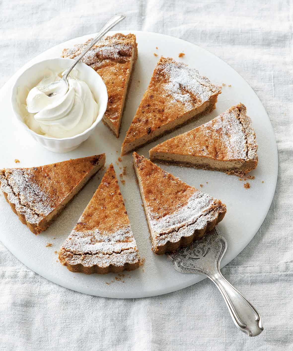 A round white plate with six slices of eggnog pie and a dish of whipped cream