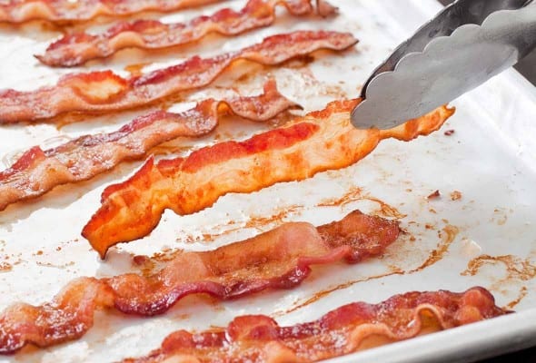 A white tray with slices of perfect baked bacon.