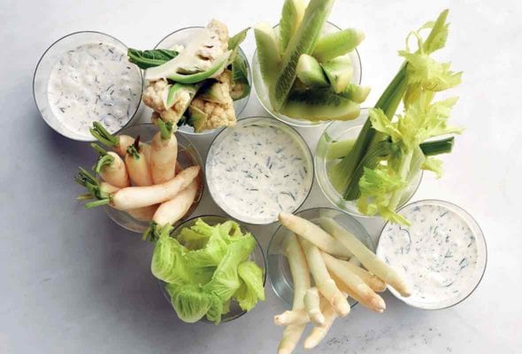 Three cups of buttermilk dressing with winter crudites in other cups.