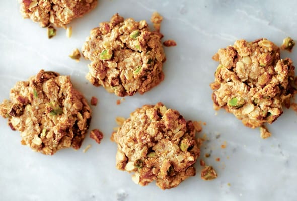 Five pistachio oatmeal cookies on a grey marble surface.