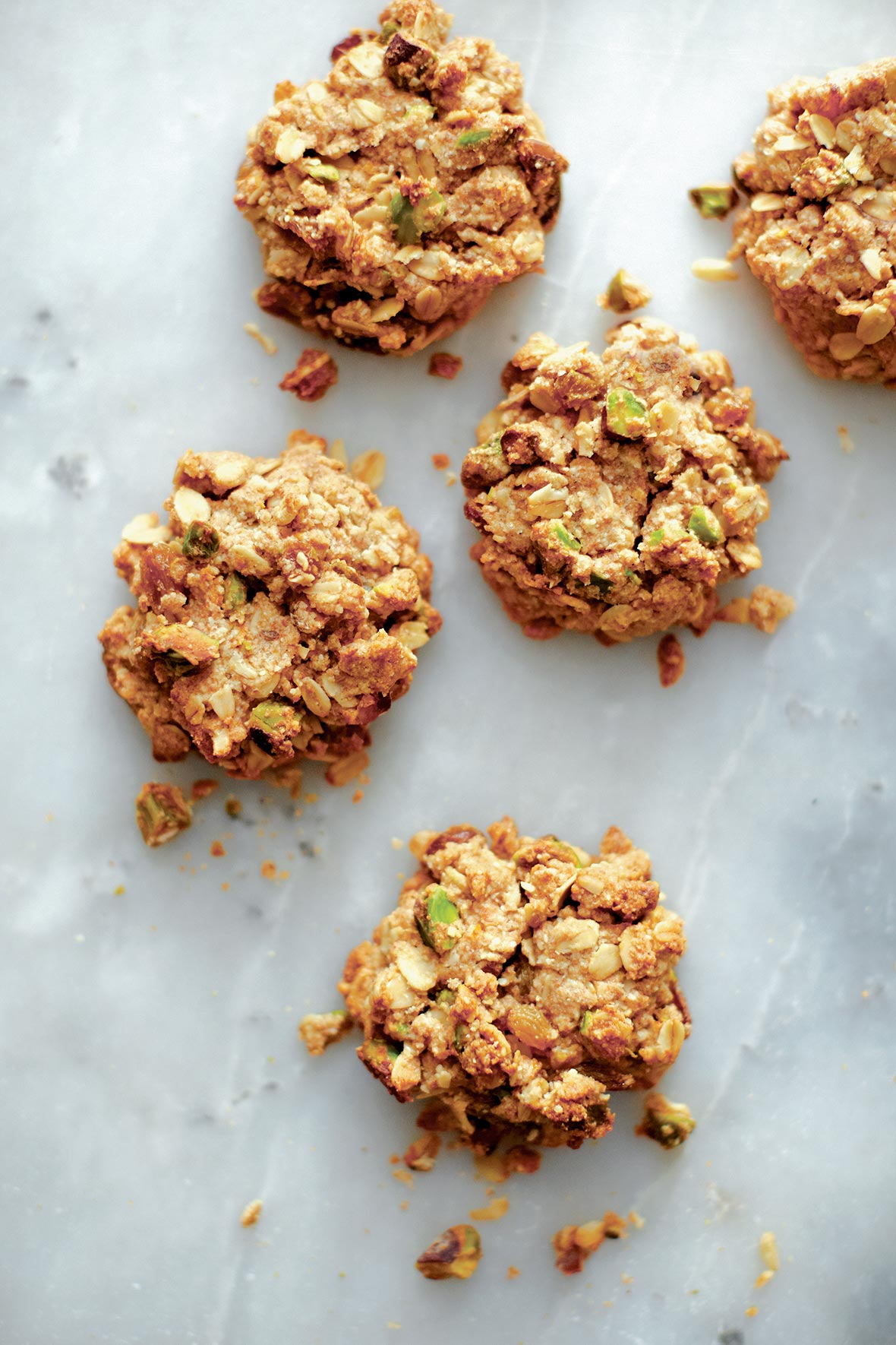 Five pistachio oatmeal cookies on a grey marble surface.