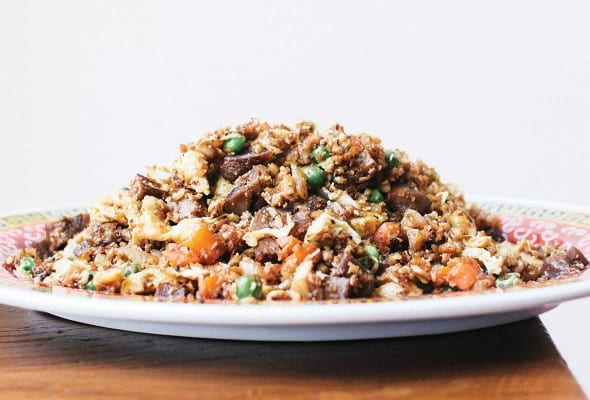 A plate mounded with cauliflower fried rice on a wooden table.