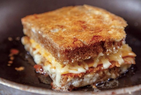 A cheese-crusted grilled cheese that is layered top and bottom with crispy Parmesan cheese in a skillet