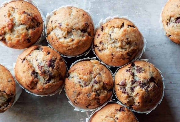Nine chocolate coconut banana muffins in paper wrappers.