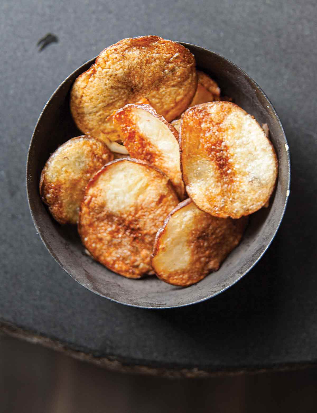 A grey bowl filled with baked potato chips
