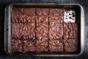 A metal baking pan of gluten free brownies with one piece missing