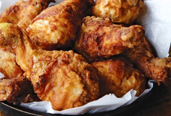 A platter of Nashville hot fried chicken with a jar of whipped butter in the background.