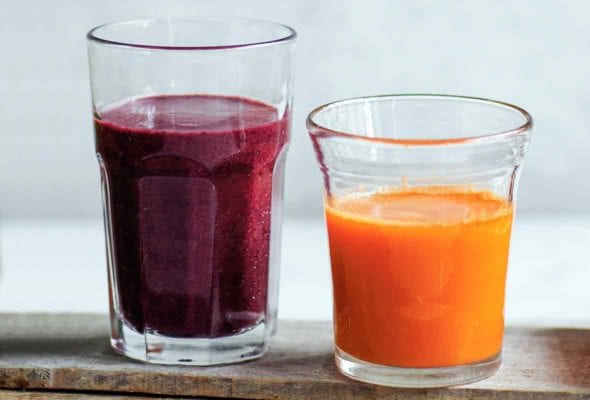 A glass of blueberry spinach smoothie on a wooden plank.