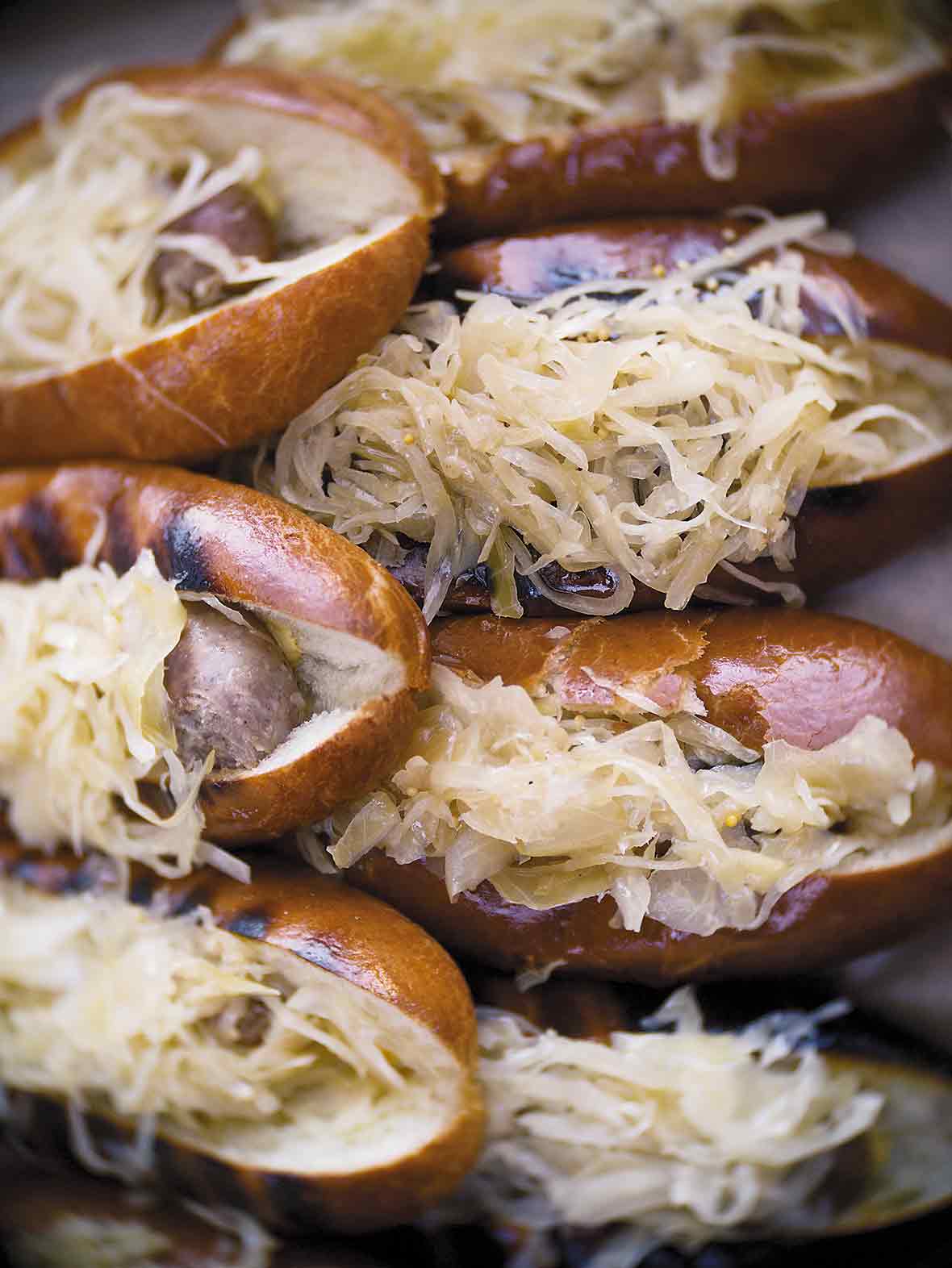 A stack of grilled beer braised bratwurst covered in sauerkraut.
