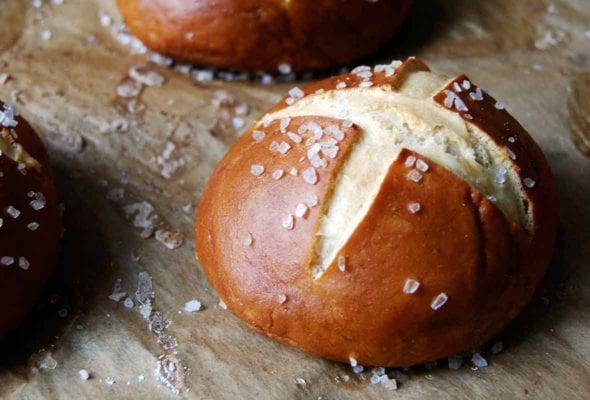 Three pretzel rolls on a piece of parchment.