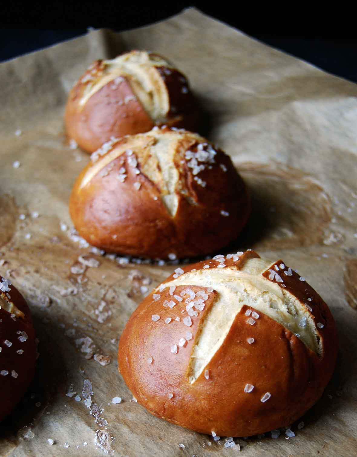 Three pretzel rolls on a piece of parchment.