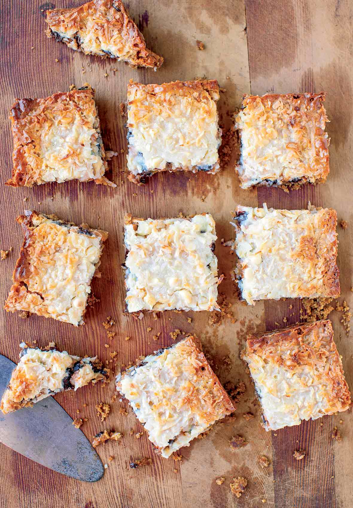A slab of pumpkin seven layer bars cut into ten pieces on a wooden board.