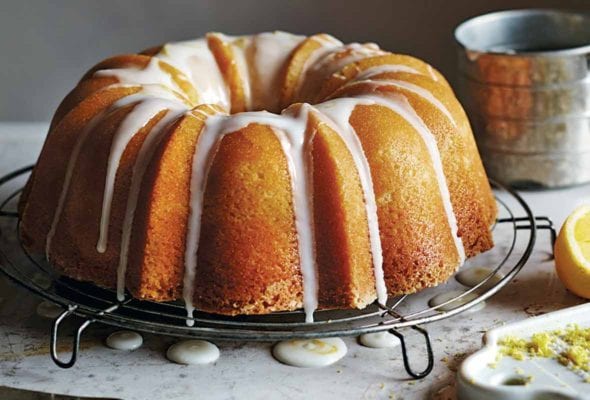 A lemon pound cake resting on a round wire rack, drizzled with a white icing glaze