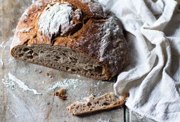 A loaf of Galician rye bread with a slice cut off to show the airy texture.