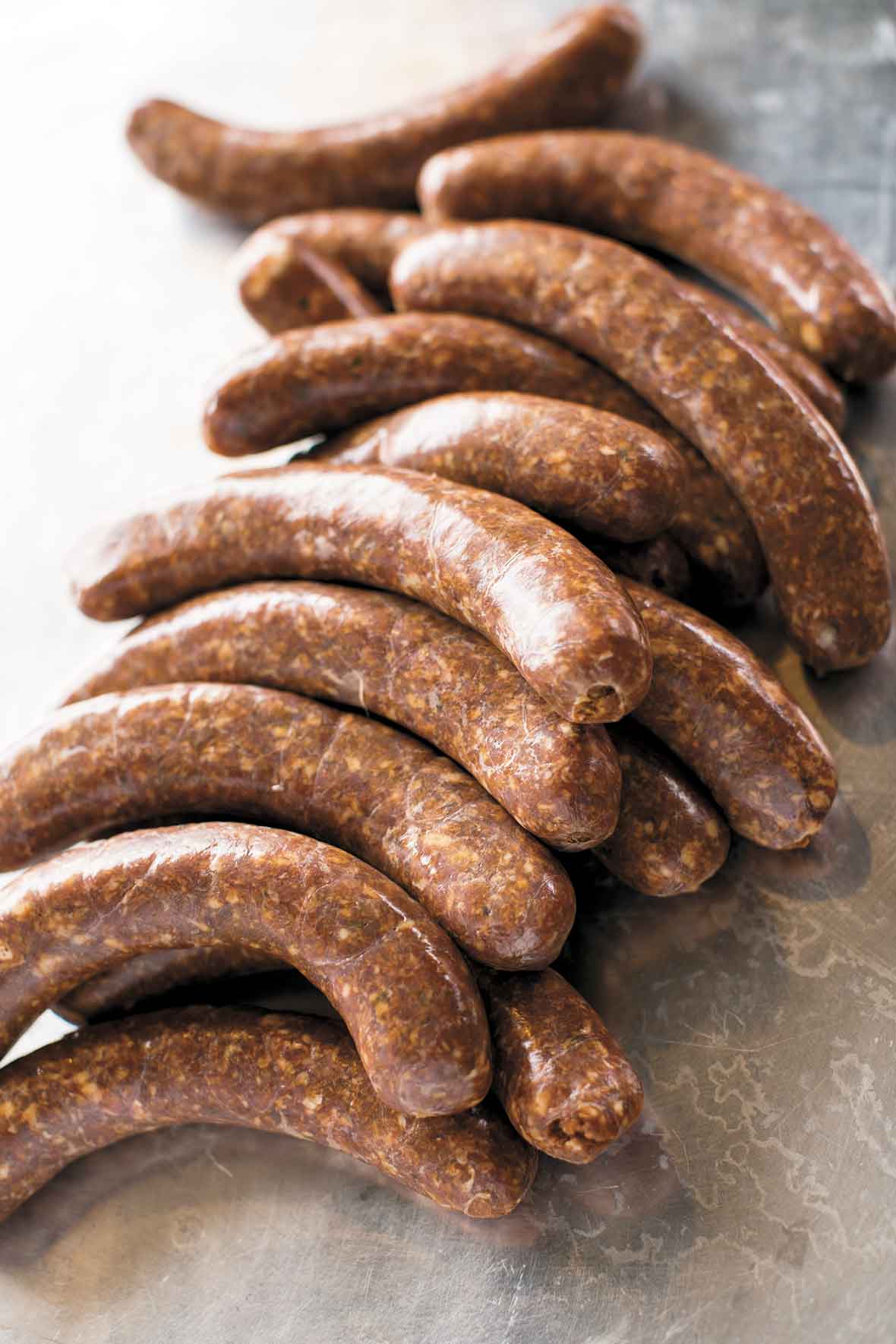 Several links of homemade chorizo on a metal surface.