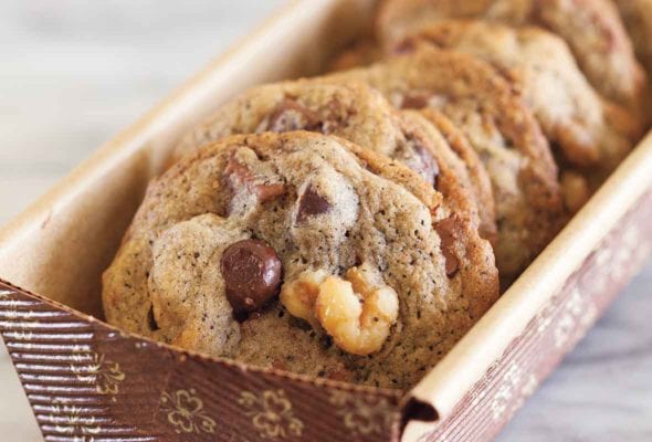 Several espresso chocolate chunk cookies in a paper container.