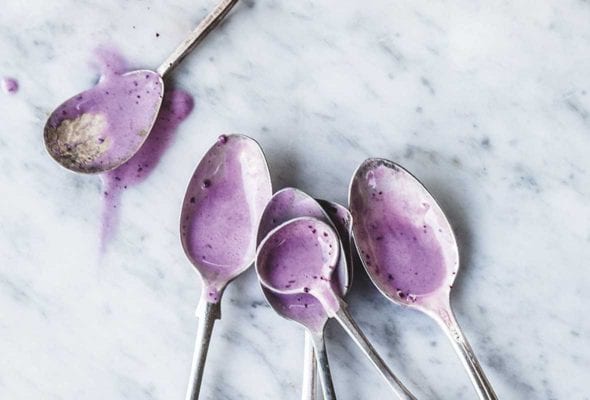 Six spoons with a little melted roasted blueberry frozen yogurt in each one.