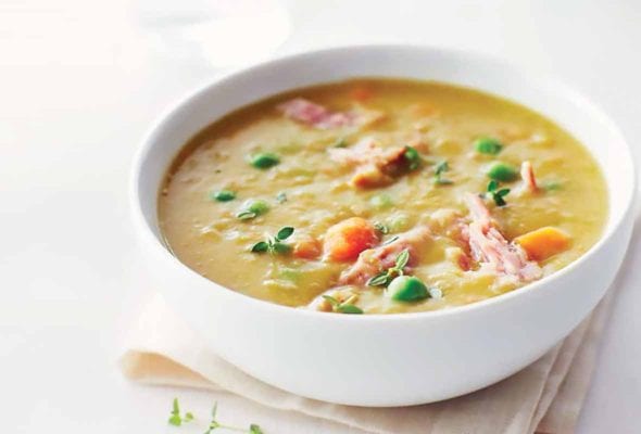 A white bowl filled with split pea soup, set on a linen napkin