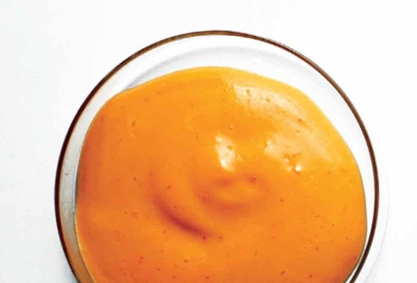 A glass bowl filled with Sriracha mayonnaise and a typed label underneath.