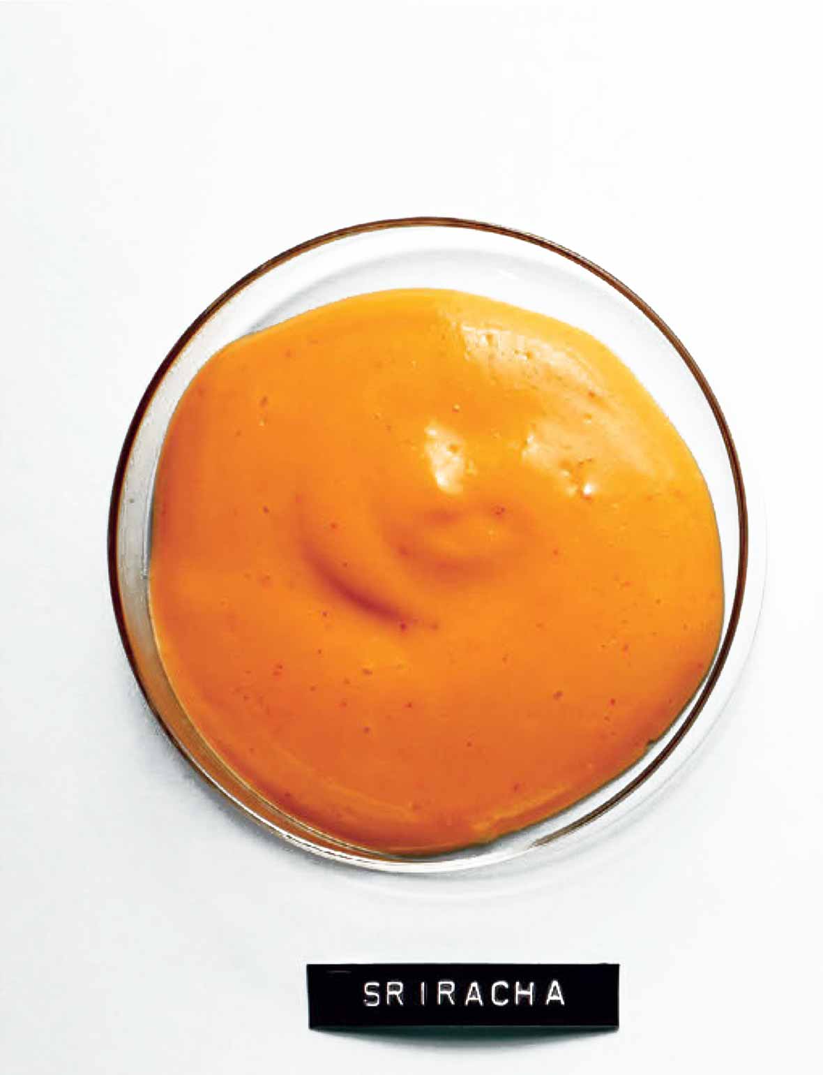 A glass bowl filled with Sriracha mayonnaise and a typed label underneath.