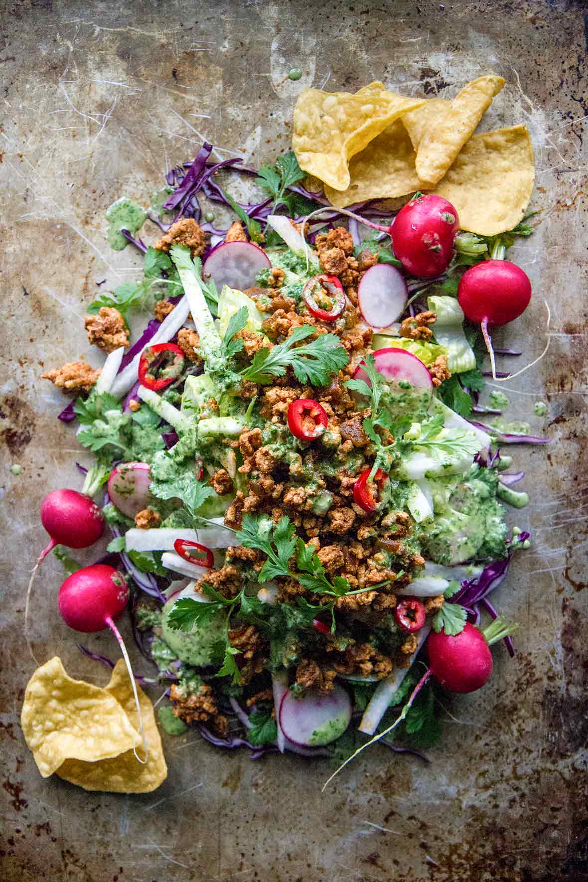 A turkey taco salad, made with ground turkey, radishes, cilantro, and jicama, mounded on a sheet pan.