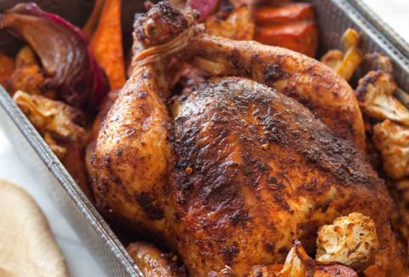 A deep roasting pan filled with roast chicken and vegetables