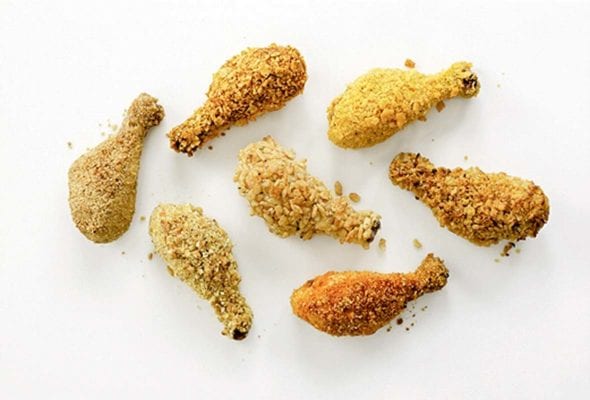 Seven oven-fried chicken drumsticks on a white surface.